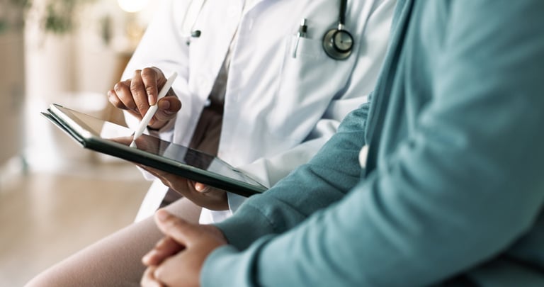 Doctor consulting with patient using tablet for medical advice at clinic