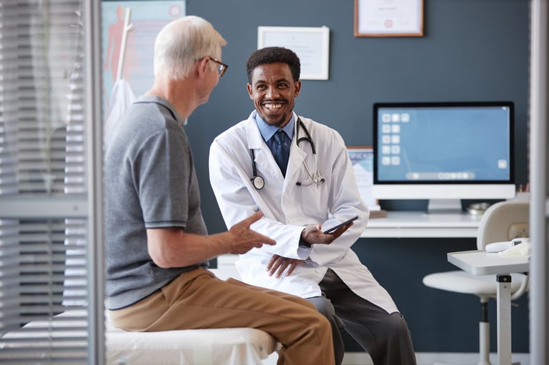 Smiling African American doctor talking to senior patient during consultation in clinic